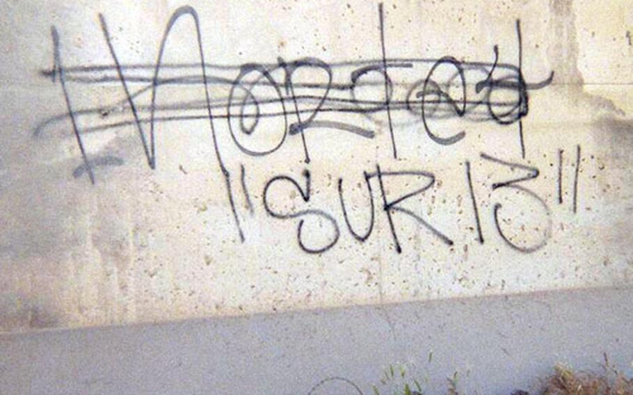 A blast wall on a U.S. base in Taji, Iraq, shows one set of gang graffiti crossing out another set.