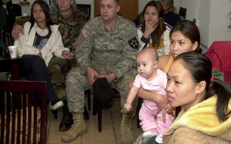 Wives and and a few of their family members listen to speakers at a foreign spouses’ monthly meeting at the Camp Casey United Service Organizations building.
