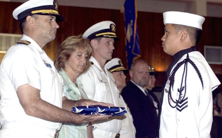 Capt. Leo Goff, commanding officer of USS Frank Cable, receives a folded flag for the Valentine family at a memorial service held for Fireman Jack Valentine, Dec. 10 at U.S. Naval Base Guam Chapel.