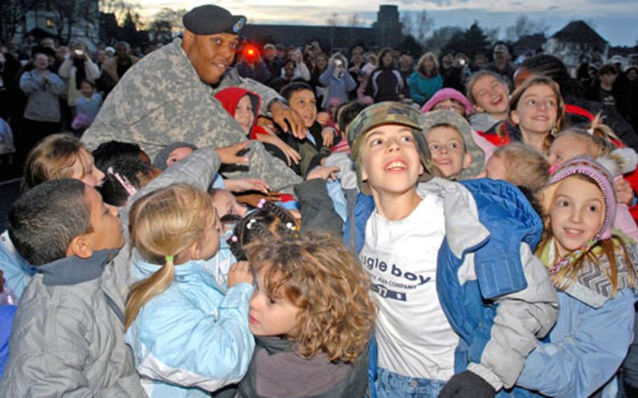 Children of the Friedberg, Germany, community help rear detachment commander Maj. Tony Perry flip the switch to light the community Christmas tree in front of 1st Brigade headquarters on Ray Barracks earlier this month. Many of the children have a parent deployed to Iraq.