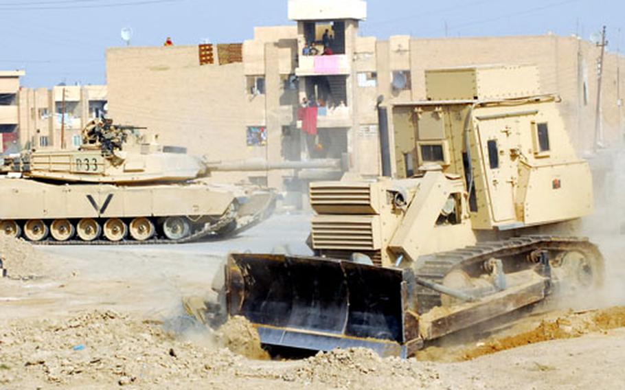 A bulldozer with the 19th Engineer Battalion clears debris from a street in Baqouba recently. One of the battalion's chief duties is to repair roadside bomb craters in Iraqi streets and clear shoulders of debris that can be used to conceal insurgent gunmen or explosives.