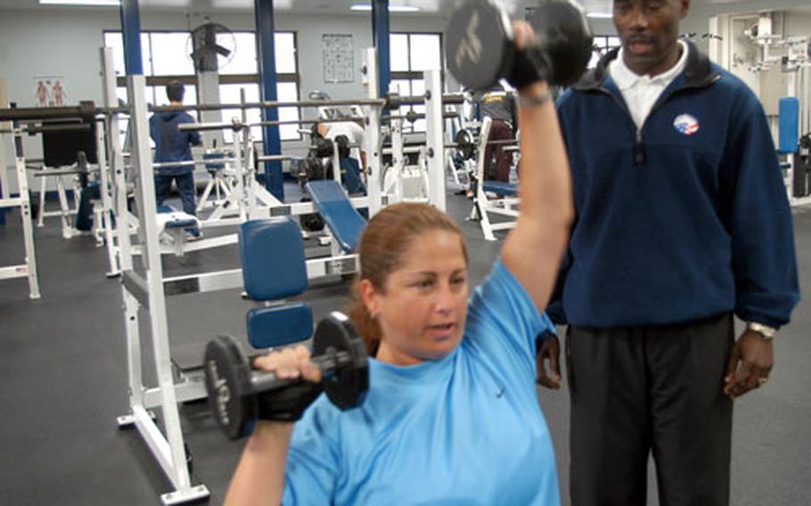 Personal fitness trainer Gilbert Moss spots Air Force spouse Jackie Alexander during a workout this week at the Potter Fitness Center.