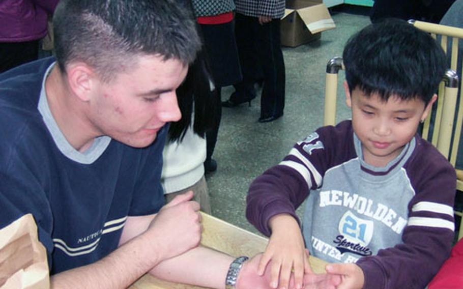 Army Pvt. Tyler Snapp plays with Kim Jung-wan, 7, during a visit to the Hanvit school for the blind during a Dec. 14 holiday party.