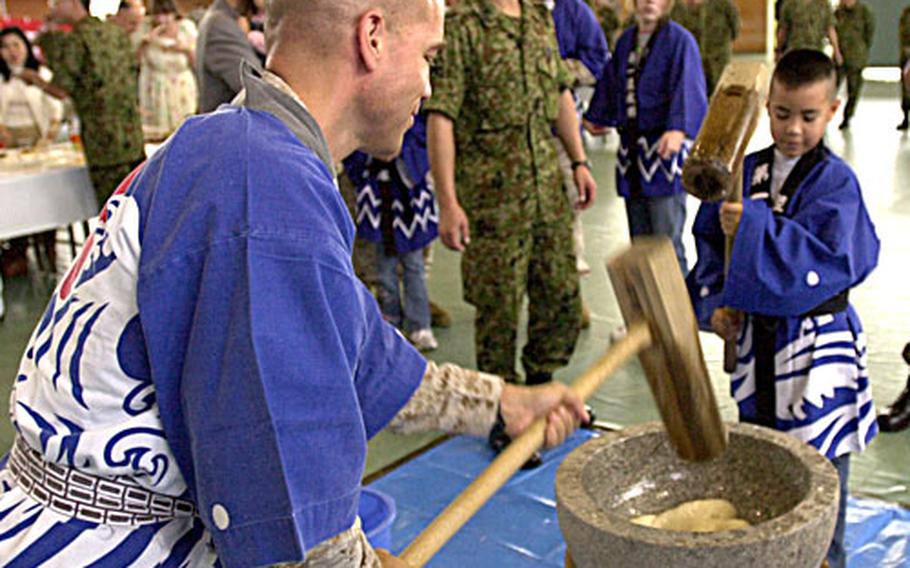 Col. James Adams, with 1st Marine Aircraft Wing, and his son William, 8, pound rice into a paste used to make mochi, a Japanese rice cake traditionally eaten during the new year season, at the Japanese Ground Self-Defense Force&#39;s 2006 Rice Pounding Ceremony at Camp Naha, Okinawa, on Wednesday. William said the mallet was heavy, but it was fun to swing and he planned to try some of the mochi balls he helped pound.