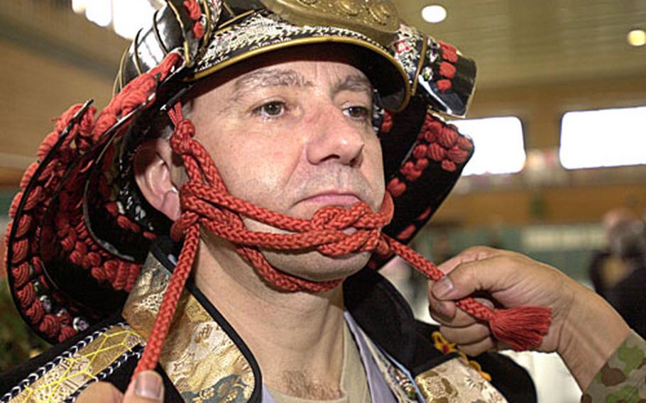 Army Lt. Col. Timothy Tuckey, with the 10th Army Support Group, gets strapped into a samuri helmet and the rest of the samuri outfit at the 2006 Rice Pounding Ceremony. Of wearing the samuri outfit, Tuckey said, "It&#39;s more comfortable than Army body armor."
