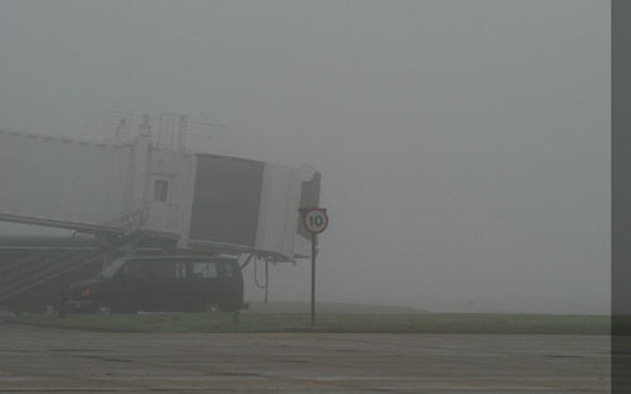The jetway at the RAF Mildenhall, England, passenger terminal sticks out of the thick fog that has shrouded much of England for several days. The diminished visibility caused delays at airports across the country.