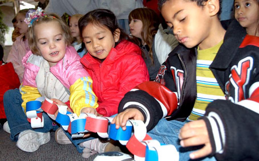 Sollars Elementary School kindergartners, from left, Samantha Arnold, Aja Martinez and Maurice Robinson hold a paper chain they decorated for the Christmas tree for deployed parents on Misawa Air Base, Japan. The “Lunch Bunch” students recently helped prepare the tree at the Airman and Family Readiness Center with other kids on base who have a parent deployed during the holidays.
