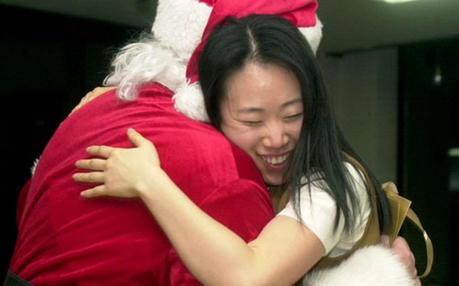 A teacher gets a big hug from Santa Claus Friday night at the Young Nak orphanage in Seoul. Servicemembers distributed more than 100 gifts at the Noncommissioned Officers Association-sponsored volunteer event.