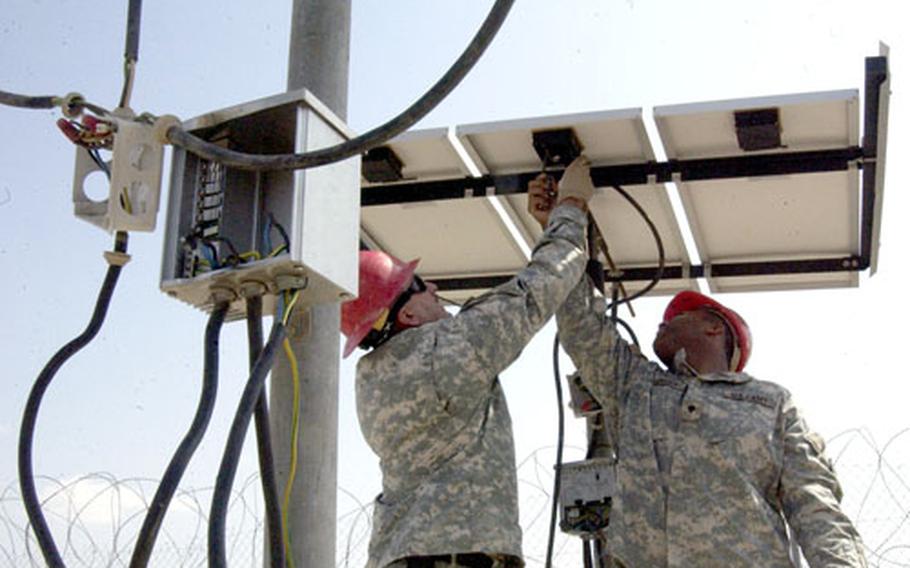Damaged control boxes dangle from wires as Sgt. Bruce Weckman, 46, of Pratville, Ala. (right) and Spec. Alonzo Henderson, 20, of Montgomery, Ala., remove a damaged solar cell from a remote well and pumping station in Djibouti on Saturday.