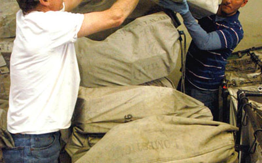 Mike Dean, left, and Petty Officer 2nd Class Von Turner stack bags of mail on Tuesday, the day after Christmas, for 3rd Platoon, 566th Postal Company in Stuttgart, Germany. Turner was borrowed from the U.S. European Command to work the Christmas mail rush, while Dean is a temporary hire.