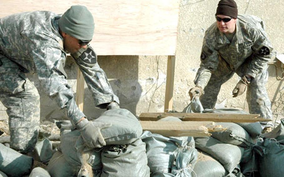 Sgt. Israel Arroyo, 22, left, of La Puente, Calif., and Sgt. Luke Draper, 25, of Long Beach, Calif., stack sandbags to protect a window shattered during a mortar attack on Forward Operating Base Loyalty.