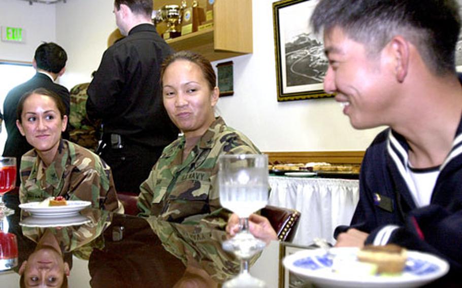 Petty Officers 1st Class Kristin Wallace and Wendy Cari, both with Commander Fleet Activity Okinawa, chat Wednesday with Seaman Yuki Ogata, a sailor with Japanese Maritime Self-Defense Force, at CFAO headquarters on Kadena. The Japanese sailors had presented their U.S. counterparts with traditional Japanese New Year decorations.