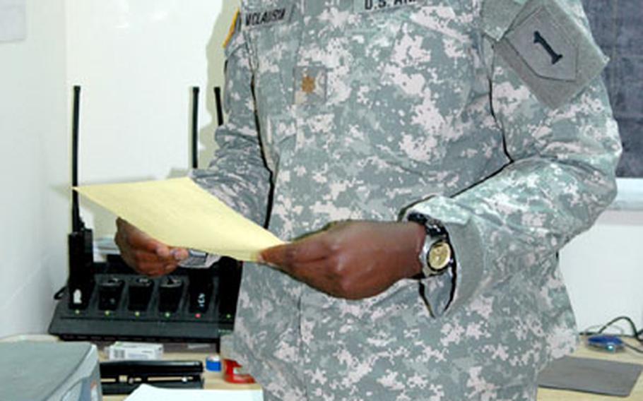 Maj. Mondrey McLaurin, Military Transition Team adviser for the 9th Iraqi Division’s Logistics and Administration Battalion, inspects a requisition form filled out on yellow paper.