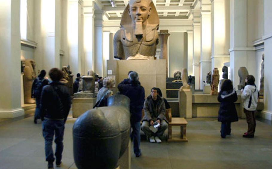 A colossal statue of a pharoah looks over visitors to the British Museum&#39;s Egyptian wing.