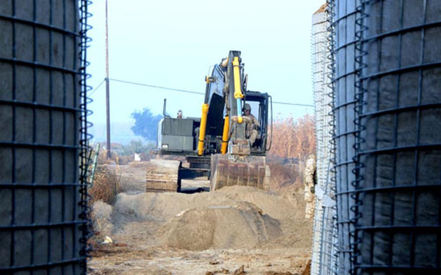 Lance Cpl. Ben Martin operates an excavator on loan from the Seabees. The 9th Engineer Support Battalion from Okinawa recently fortifed the water pump house facility with a perimeter of Hesco barriers to better protect it from insurgent attacks.