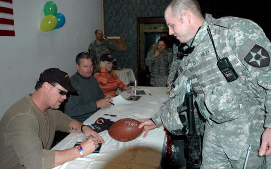 Former Chicago Bears quarterback Jim McMahon, left, signs a program for Staff Sgt. Steven Foley, 31, of Portsmouth, Ohio. Foley works in Air Defense/Air Space Management in the 2nd Brigade Combat Team’s Brigade Aviation Element.