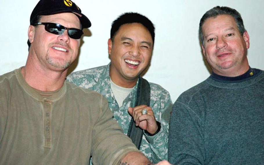 Sgt. Jovell MacAraeg, 37, of Porterville, Calif., tries on the Super Bowl XX ring belonging to Former Chicago Bears quarterback Jim McMahon, left, At right is former Chicago Bears kicker Kevin Butler. MacAraeg works for the 2nd Brigade Special Troops Battalion’s B Company, Military Intelligence.