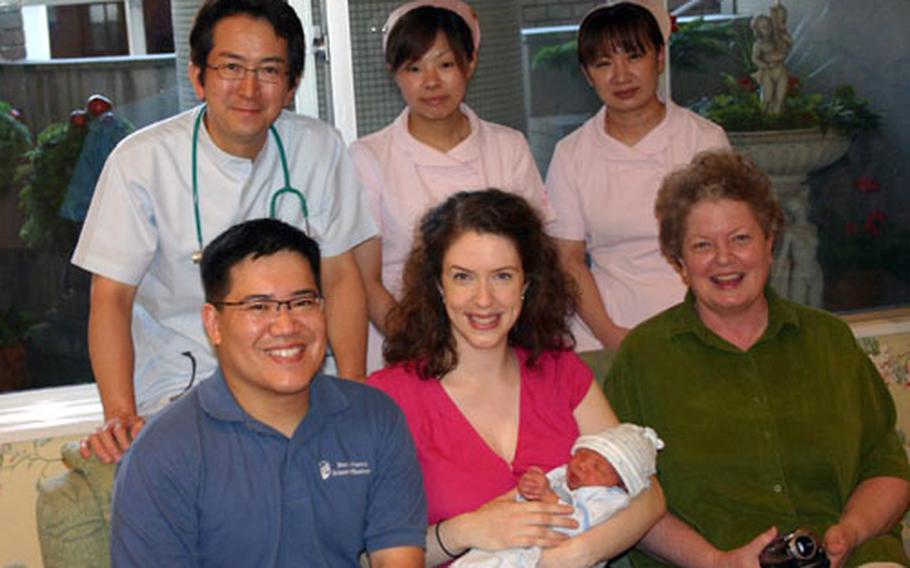 Navy Cmdr. Bernard Wang, Erin Wang (holding baby Jayden) and Erin&#39;s mom, Mary Himes, stand with Dr. Hiroshi Higashijima (top left) and two nurses. Erin gave birth last summer to baby Jayden at the Higashijima ladies clinic in Sasebo.