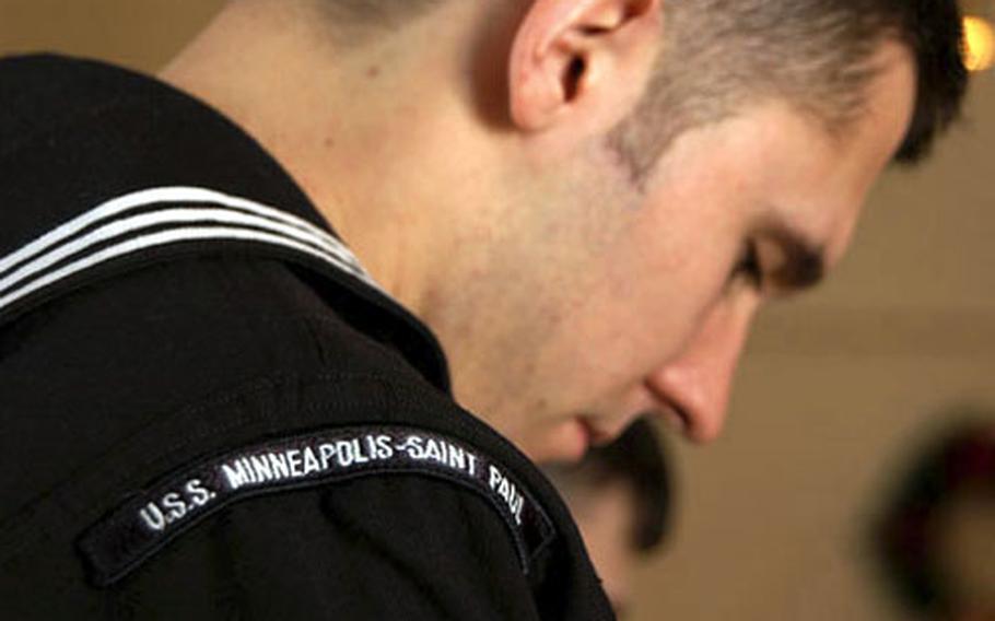 A USS Minneapolis-St. Paul crewmember bows his head in prayer at a memorial service Wednesday for Senior Chief Petty Officer Thomas E. Higgins and Petty Officer 2nd Class Michael J. Holtz at Naval Station Rota, Spain.