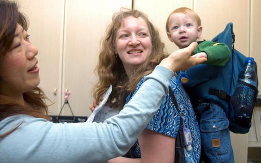 Masae Hayashi, Sugar and Spice international model division’s chief manager, greets new model 11-month-old Bryce Holbrook and his mother, Mary.