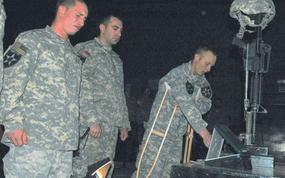 Pfc. Philip Bodine, left, 1st Lt. Jonathan Martin, center, and Pfc. Chris Heidling, right, mourn Sgt. John Michael Sullivan during a memorial service Saturday night at Forward Operating Base Loyalty in Baghdad, Iraq.