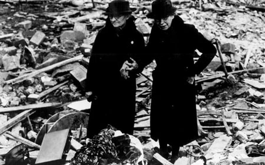 Two women stand amid the leveled ruins of the Newbury almshouse they lived in until it was bombed during the Battle of Britain in February 1943.