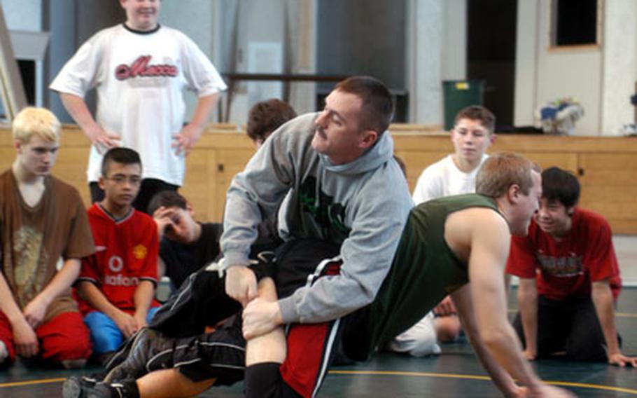 Alconbury senior Doug Bagnall (green shirt) is the Guinea pig for volunteer coach Rodney Lucas as he shows other wrestlers a takedown last week.