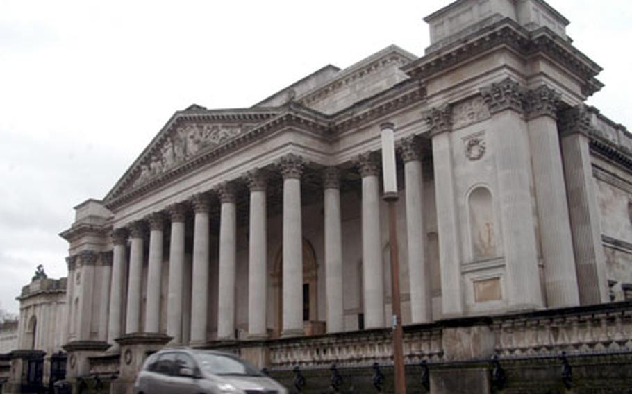 A car drives past a stone columned entrance to the Fitzwilliam Museum in Cambridge. The museum boasts collections of fine art and ancient artifacts from around the world.