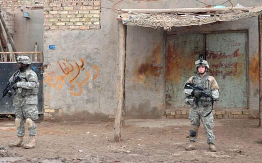 Soldiers stand guard during a dawn search for an insurgent suspected of planting roadside bombs in the mostly Shiite Baghdad neighborhood of Zafaraniya on Thursday morning. The graffiti on the wall says, roughly, that earthly matters are of no consequence, compared to Heaven and eternity.
