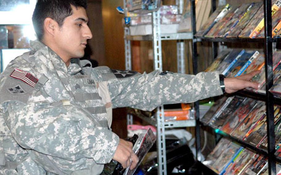 Spc. Genaro Chavez, 27, of El Paso, Texas, with Company G, 2nd Battalion, 17th Field Artillery Regiment, shops for DVDs at a small store on FOB Loyalty Thursday. Chavez said that having more Iraqi security forces in Baghdad would be good “because it will be good for Iraqi soldiers’ motivation to learn and study from what [U.S. troops] do.”