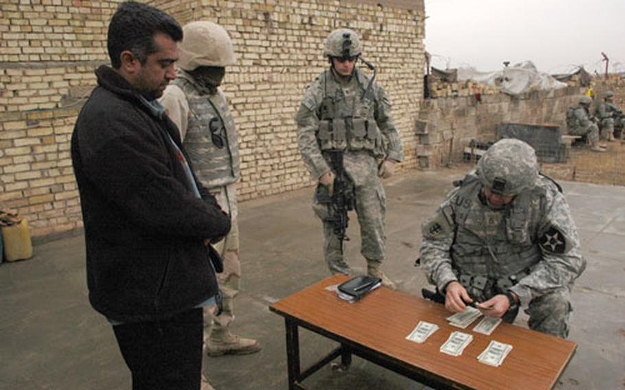 The head of the family of two women killed by a U.S artillery round on Dec. 29 accepts a condolence payment from the 2nd Infantry Division’s 2nd Brigade Combat Team chaplain’s assistant, Staff Sgt. Malcom Nichols. Watching the proceedings, center, is 1st Lt. Josh Mantz, of the 1st Cavalry Division’s 1st Battalion, 8th Cavalry Regiment, 2nd Brigade Combat Team. Mantz found the family while his unit was doing a foot patrol in their neighborhood last week.