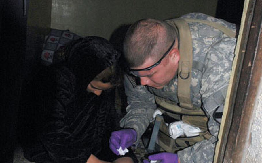 Hajil, an Iraqi girl hit in the leg by shrapnel from a U.S. artillery round on Dec. 29, helps Sgt. Bryan Hays, 34, a medic from Haughton, La., as he works on her wound. Hays is with the 1st Cavalry Division’s 1st Battalion, 8th Cavalry Regiment, which found the family affected by the artillery round. Hays has been supervising Hajil’s medical care.