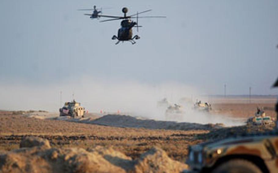Ground forces of 2nd Battalion, 35th Infantry Regiment, 25th Infantry Division, stage outside of a village in the Rashaad Valley as a team of OH-58D Kiowa Warriors fly overhead.