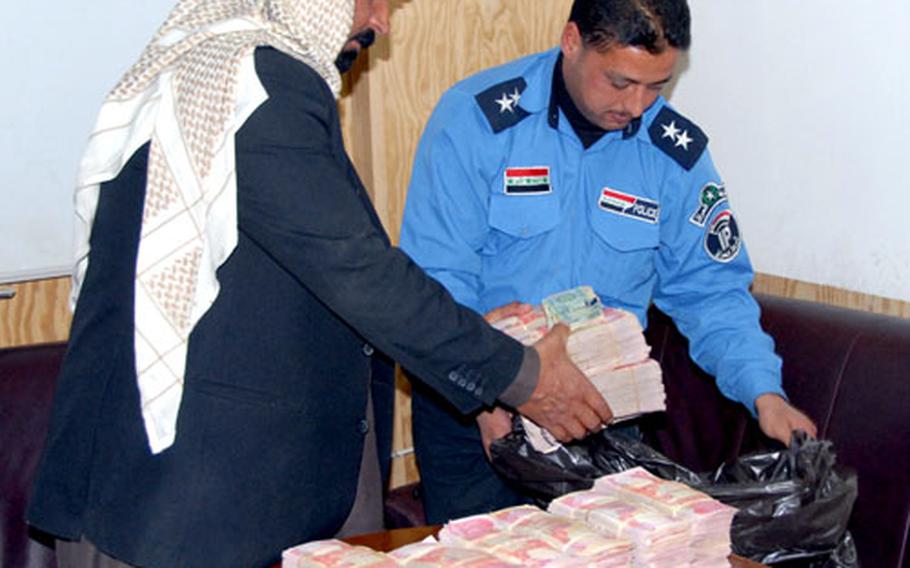 Sheik Mohammed Farhan Al-Hayis, president of the Jazeera Council, puts about $250,000 worth of dinars into a garbage bag. The money is for renovation projects that the council will be in charge of prioritizing.