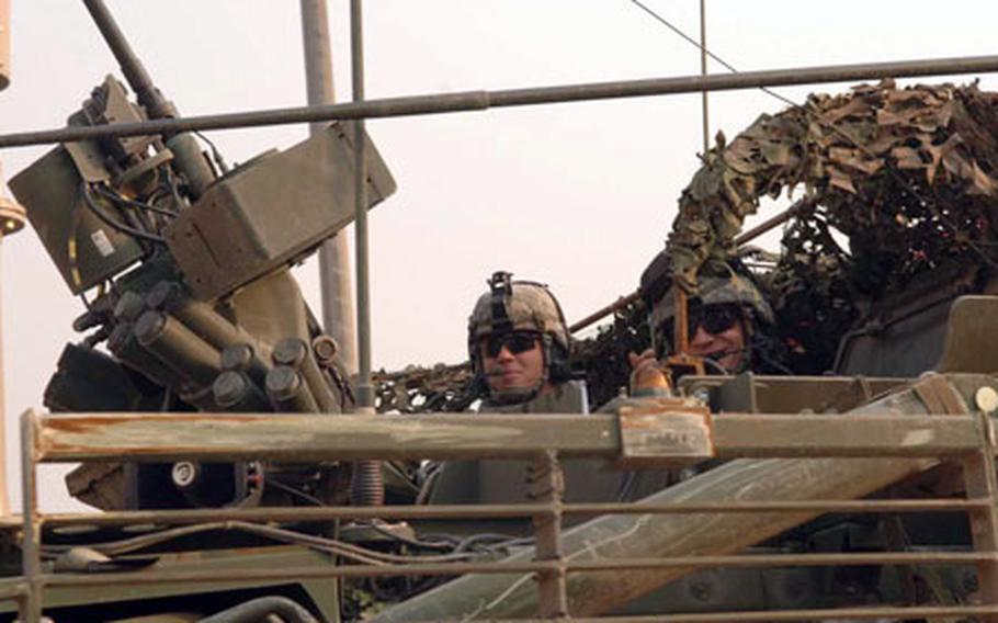 Crewmen in a Stryker wheeled combat vehicle wave as they drive through Forward Operating Base Loyalty in Baghdad, Iraq, after a recent mission.