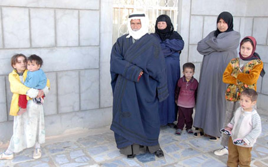 A disgruntled family - the children clutching Iraqi Police stickers given to them earlier, wearily watches Iraqi police and soldiers leave their house after having their weapons confiscated. The man lied about having weapons, and when the police discovered them he said he found them in the trash. He was almost detained by the American forces, but the Iraqi police said he could stay in the neighborhood.