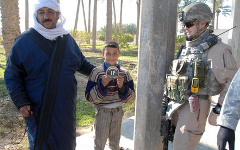 A local Albu Faraj child holds up the Iraqi Police sticker given to him by Sgt. Stephen Burnham, 30, of the 9th Psychological Operations Battalion out of Fort Bragg, NC. Burnham, who is assigned to Task Force 2-37, went on the patrol with the Iraqi police to assess how the locals feel about the police. The man showed Burnham where the insurgents shot at his house, hitting his car.