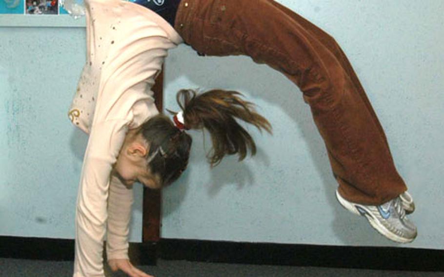 Ten-year-old Rachel Pagio folds herself over in a back handspring in a hallway at Alconbury Elementary School, a trick she can accomplish in even very small spaces.