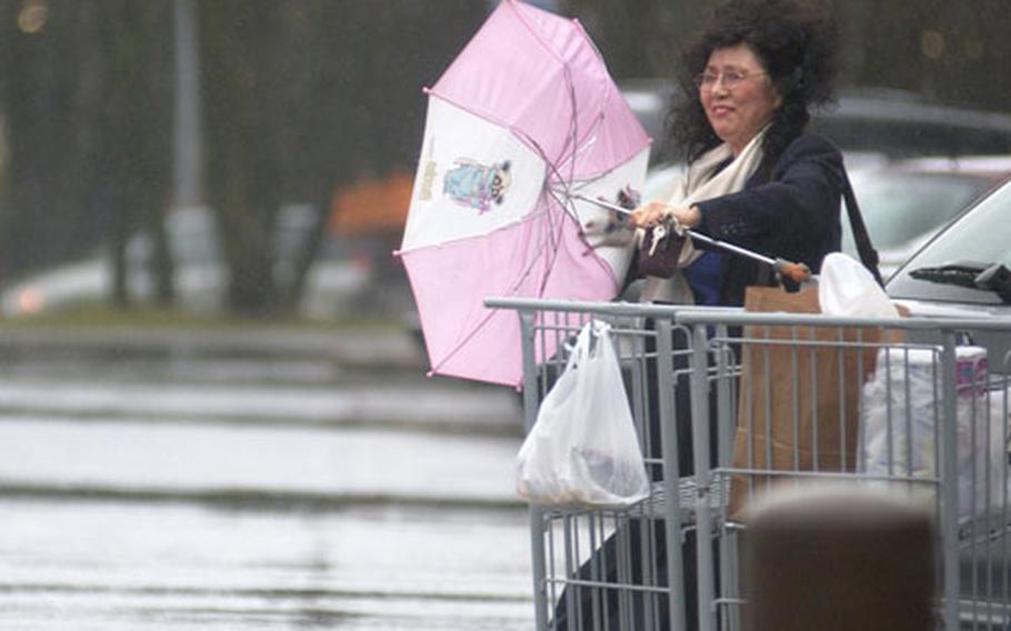 A commissary patron at Ramstein Air Base, Germany, fights the strong winds by her car Thursday. The 21st Operational Weather Squadron released a severe weather warning across Germany with forecasting winds greater than or equal to 52 miles per hour.