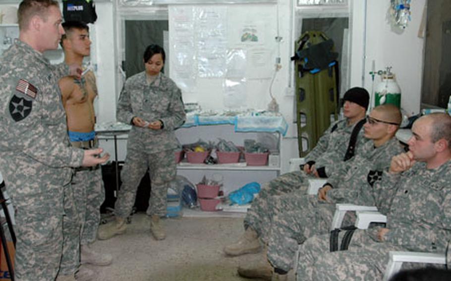 Fellow medic Pfc. Celina Antonio, 19, of Loma Linda, Calif., assists Capt. Surrett in his demonstration. Watching are, from left: Spcs. Jonathan Ford, 22, or Columbus, Ohio; Anthony Wilson, 25, Toms River, N.J.; and Bryan Pitman, 24, of Riverside, Calif.