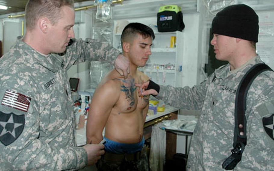 Capt. Surrett shows Spc. Jonathan Ford, 22, of Columbus, Ohio, where to place the 14-gauge chest decompression needle on Spc. Dover.