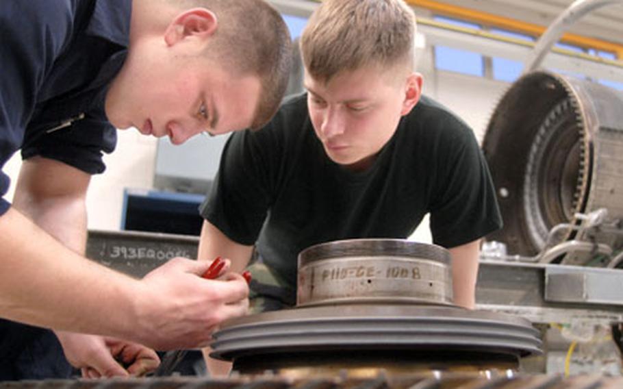 Airman 1st Class Payton Henley, right, watches as Senior Airman Robert Marcy, a jet engine mechanic assigned to the 52nd Component Maintenance Squadron, removes a defective seal from a high pressure turbine rotor used in an F110 engine Thursday at Spangdahlem Air Base, Germany.