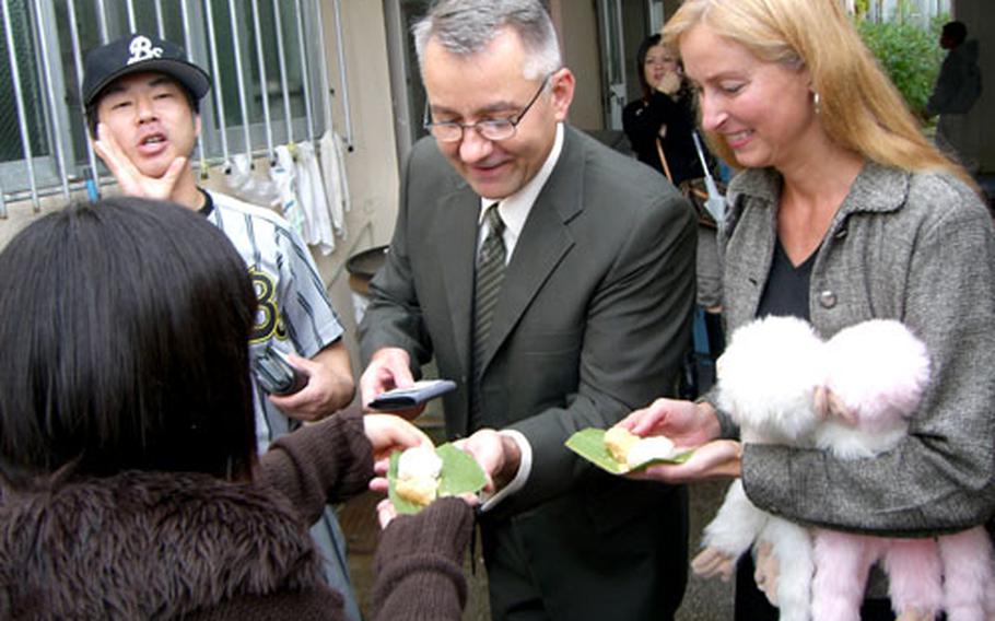 A student of Misato Children&#39;s Home offers Mochi (pounded rice cake) Sunday to her volunteer English instructors, Army Lt. Col. Timothy Tuckey and his wife, Reba, during an annual New Year party at the home in Okinawa City. The Tuckeys have been teaching English at the home for the past two years.