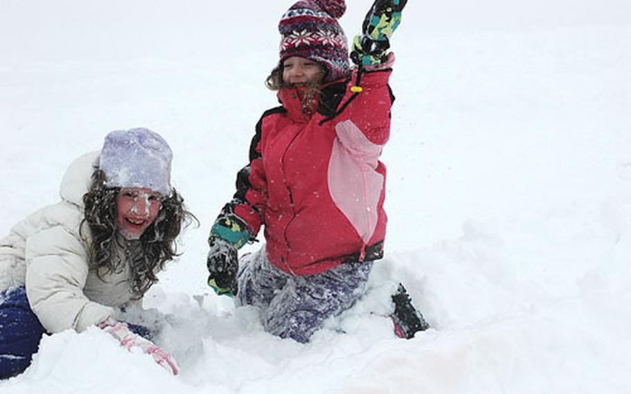Rachel Bragg, 8, left, and her 5-year-old sister, Grace, climb out of the snow after wiping out during a sled run Wednesday at Robinson Barracks in Stuttgart, Germany. The girls were celebrating a day off from school after Stuttgart received 12 inches of snow overnight.