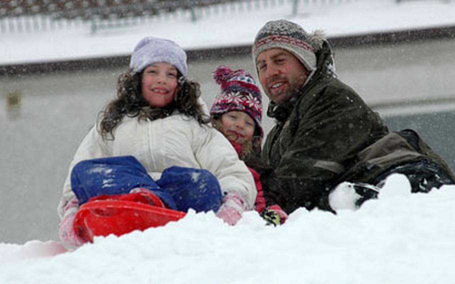 Rachel Bragg, 8, left, her sister, Grace, 5, get ready for a sled run with help from their father, Army Maj. Andrew Bragg, on Wednesday at Robinson Barracks in Stuttgart, Germany. The girls were celebrating a day off from school after Stuttgart received 12 inches of snow overnight.