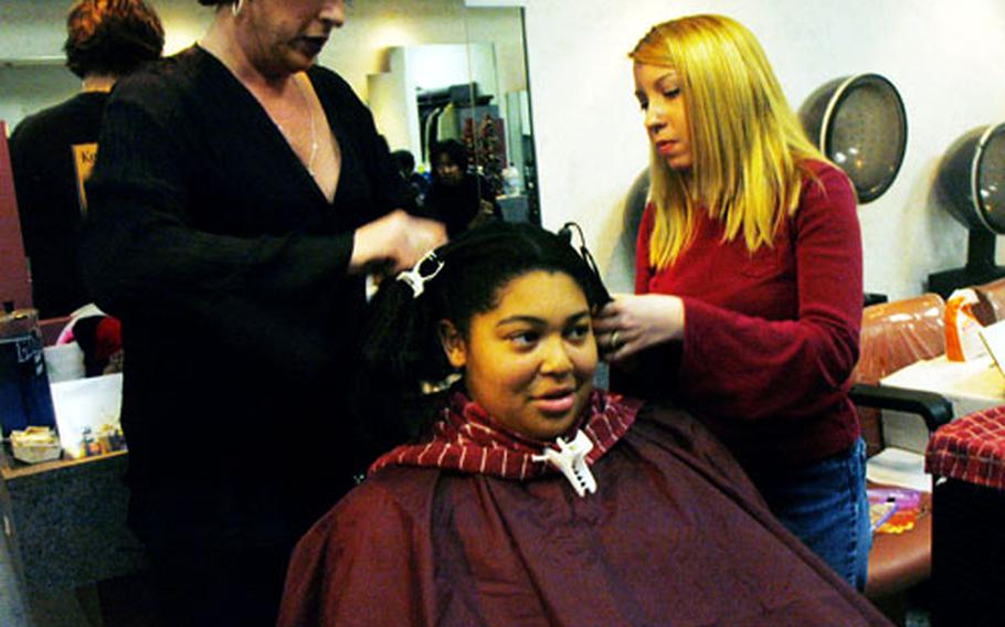 Navy Exchange hair stylists Lisa Haddock and Tressa Horner practice ethnic hair treatment on Christian Garner Tuesday in a hands-on course designed to trim waiting lists for multicultural hair care on Japan&#39;s Navy bases.