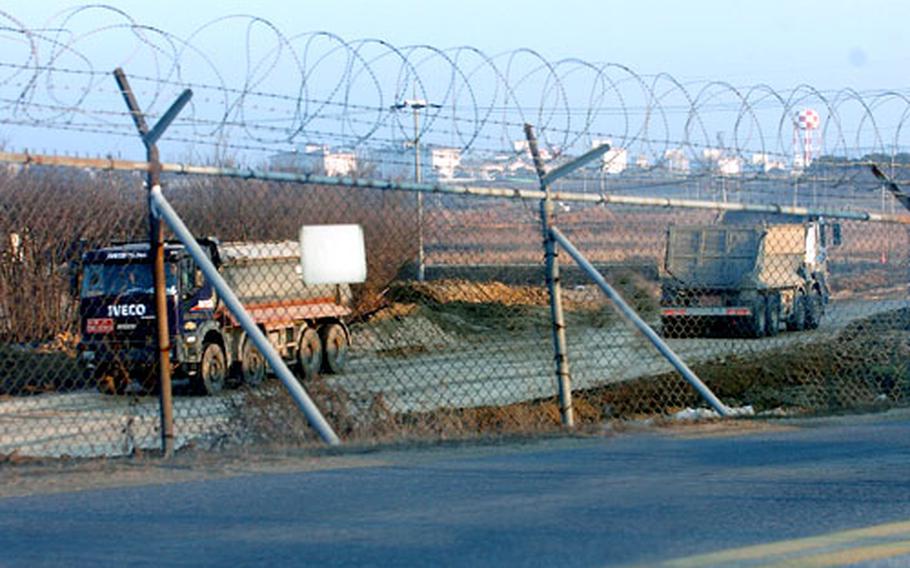 Trucks helping ready land for the eventual expansion of Camp Humphreys in South Korea move down a road outside the post’s perimeter fence Wednesday. Work has begun on the first portion of a 2,328-acre tract that will eventually be part of the expanded post, which will triple in size to become the U.S. military’s flagship installation in South Korea.