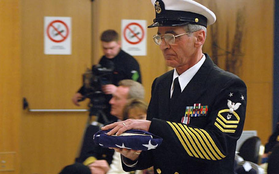 Master Chief Petty Officer Doug Forziati carries a folded American flag after it was passed during the "Olde Glory Presentation," a naval retirement tradition in which the text of the ceremony is read to music. It is divided into the number of segments needed to represent each of the ranks held by the retiring member during his or her career.