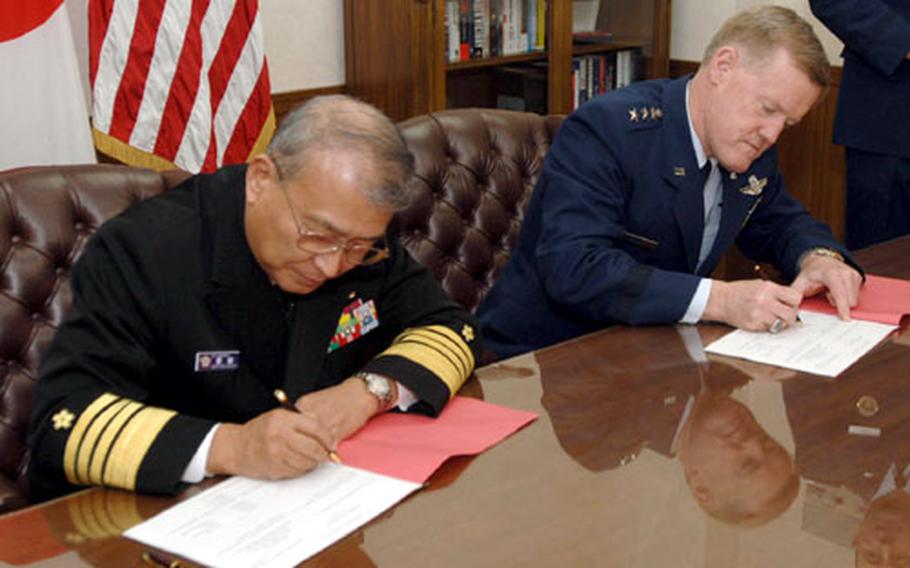 Adm. Takashi Saito, chief of staff of Japan’s Joint Staff Office, and Lt. Gen. Bruce A. Wright, the U.S. Forces Japan and 5th Air Force commander, sign documents Wednesday at Yokota Air Base, Japan, marking the formal agreement to conduct Keen Edge, a joint and bilateral command post exercise.