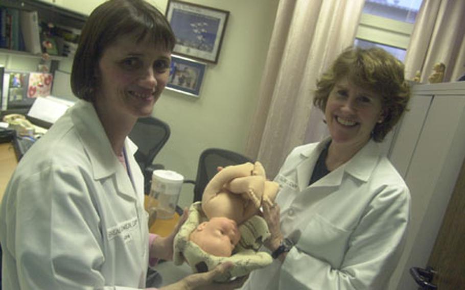 Where&#39;s the stork? Air Force Lt. Cols. Brenda Owen, left, and Mary Claire Wahl hold a model of the birth process. The certified nurse midwifes will lead the "Centering Pregnancy" program at Landstuhl Regional Medical Center, in which pregnant women receive prenatal care in a group setting.
